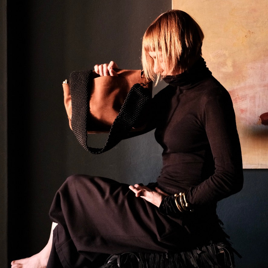 model dressed in black holding ogda shoulder bag in cognac leather
