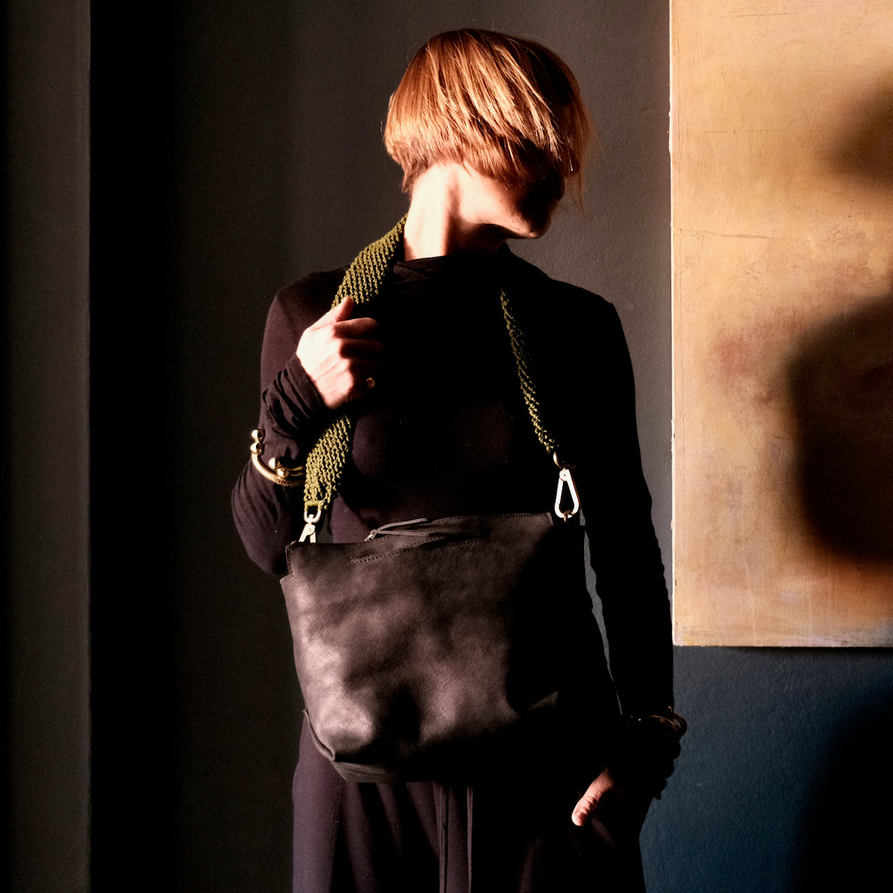 model wearing a black leather ogda shoulder bag wity olive macrame strap