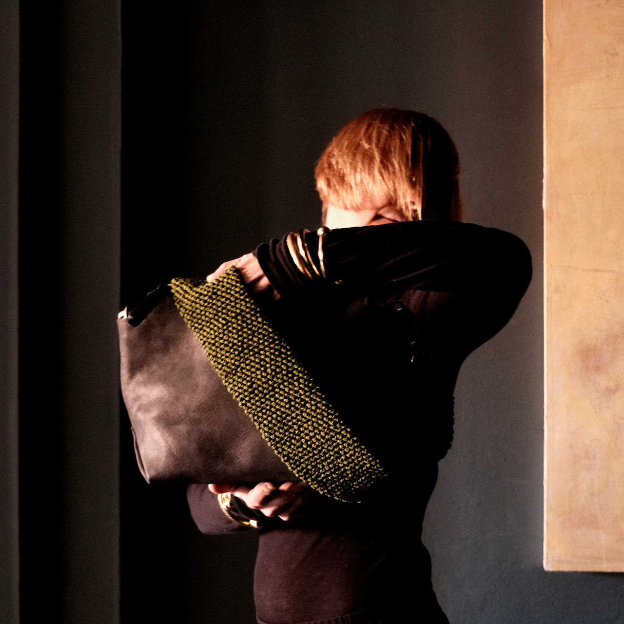 model holding a black ogda shoulder bag with olive coloured macrame strap